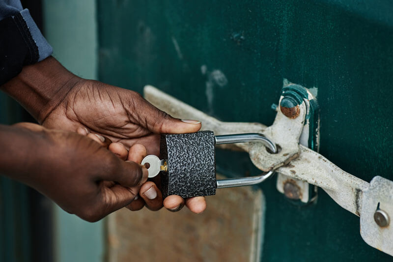 Man unlocking a padlock with key.